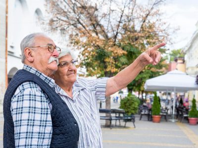 senior couple pointing finger in walking street