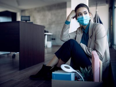 Distraught businesswoman sitting on the floor and thinking after getting fired from work during coronavirus pandemic.