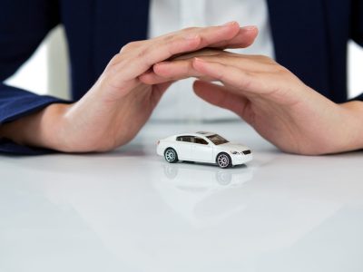Mid section of businesswoman protecting toy car with hands