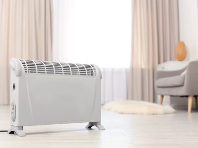Modern electric heater on floor at home. Space for text