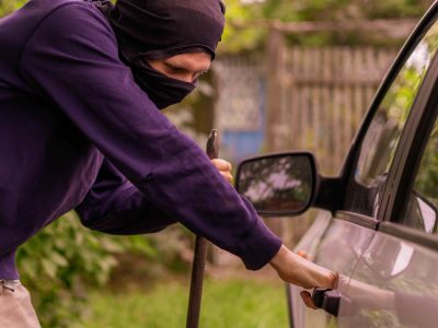 robber standing next to the car and trying to steal things