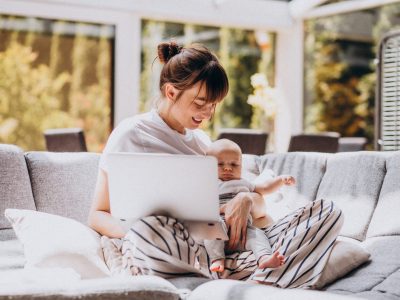 Young mother with her kid working at home on a computer