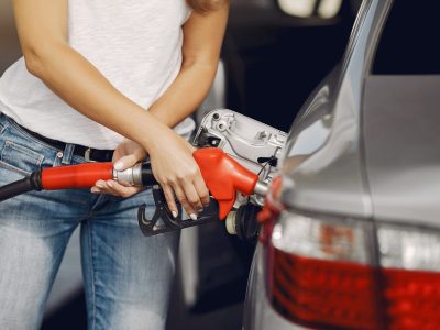Woman on a gas station. Lady in a white t-shirt. Woman near the car.