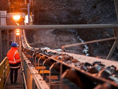 Nyngan Australia June 20th 2012 : Shallow depth of field image of a miner inspecting ore rocks on a conveyor in NSW Australia