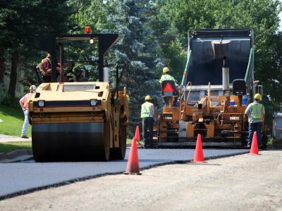 An asphalt spreader is used to place the first layer of asphalt on a city street renewal project.