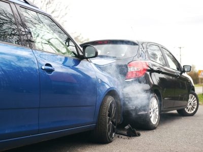 Two cars involved in traffic accident on side of the road with damage to bonnet and fender