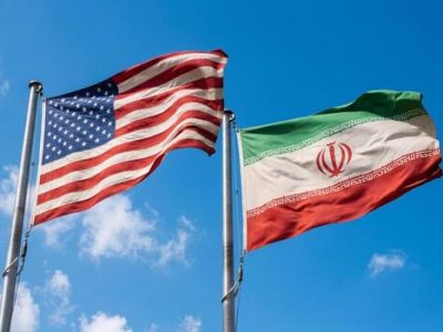 usa-and-iran-national-flags-waving-in-wind-against-blue-sky-photo