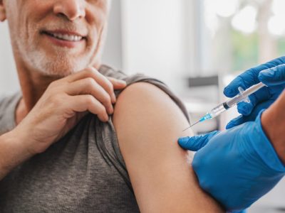 Doctor making injection to senior patient in clinic